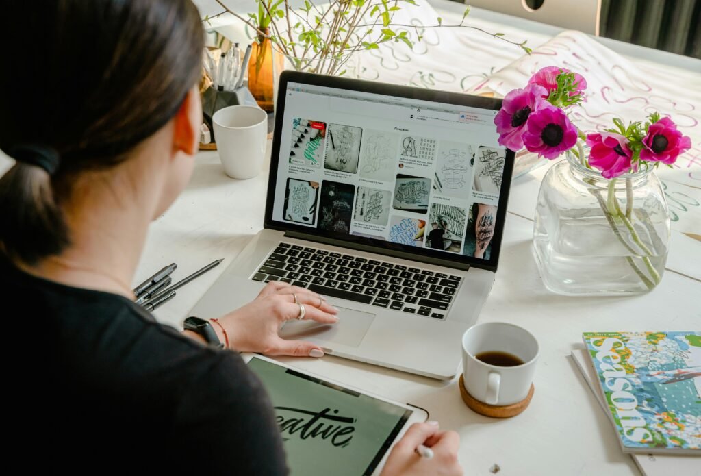 pexels-photo-4348404-4348404 Graphic Designer, Woman in a creative workspace using a laptop and tablet for calligraphy. Artistic and tech-driven environment.